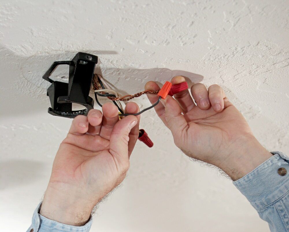 Hands Connecting Electrical Wires with Wire Nuts at A Ceiling Fixture Junction Box — AC/DC Electrical, Air Conditioning & Refrigeration In Gatton, QLD