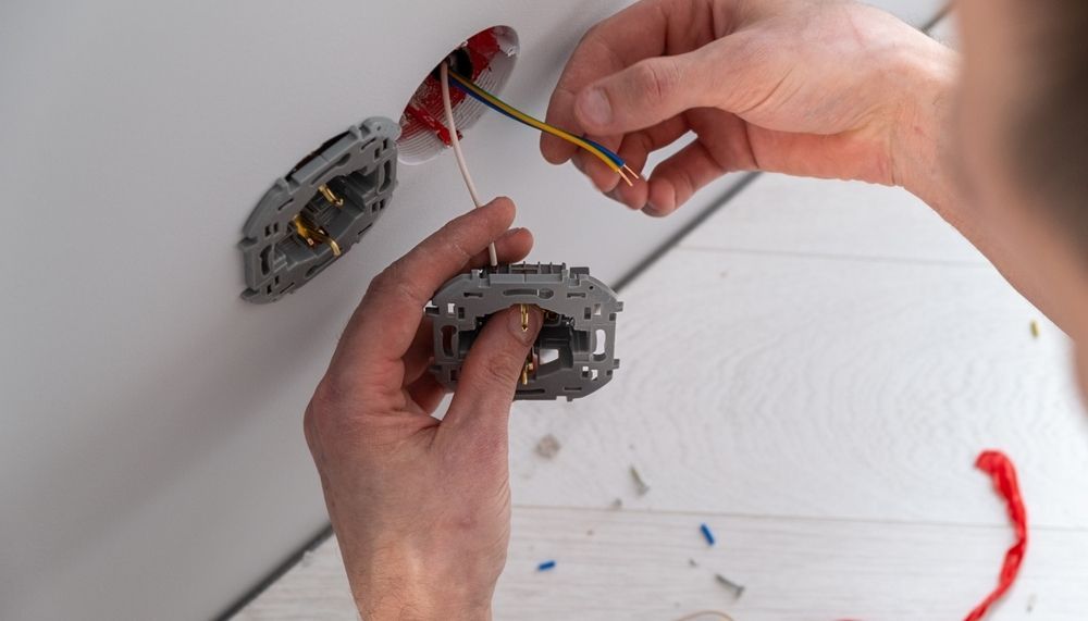 Close-Up of Hands Connecting Electrical Wires to An Outlet Mechanism Inside a Wall — AC/DC Electrical, Air Conditioning & Refrigeration In Rockhampton, QLD