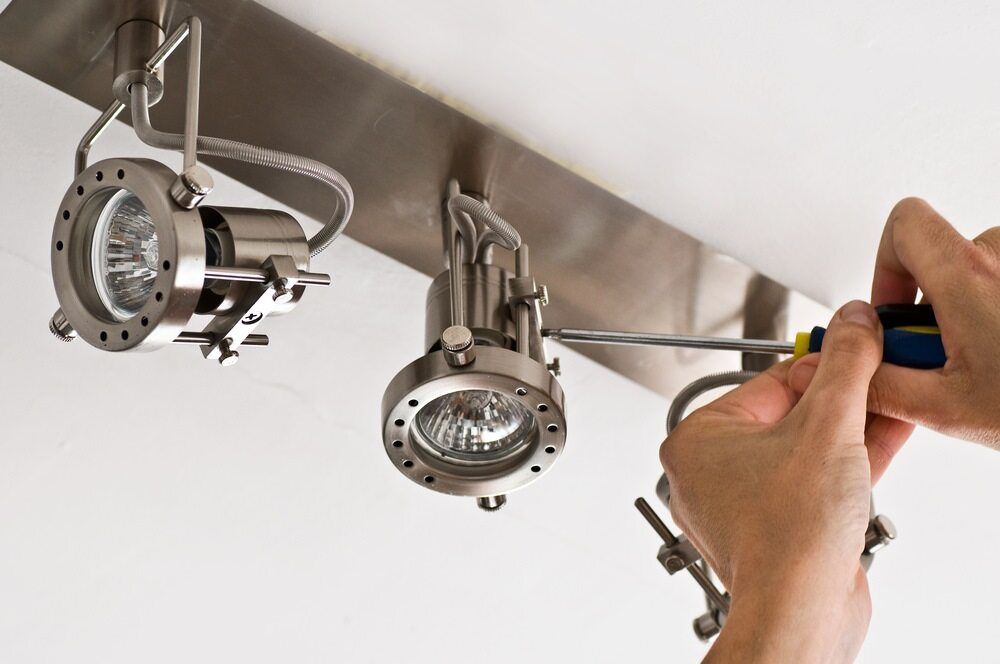 Hands Using a Screwdriver to Adjust a Modern, Brushed-Metal Track Lighting Fixture — AC/DC Electrical, Air Conditioning & Refrigeration In Murphy's Creek, QLD
