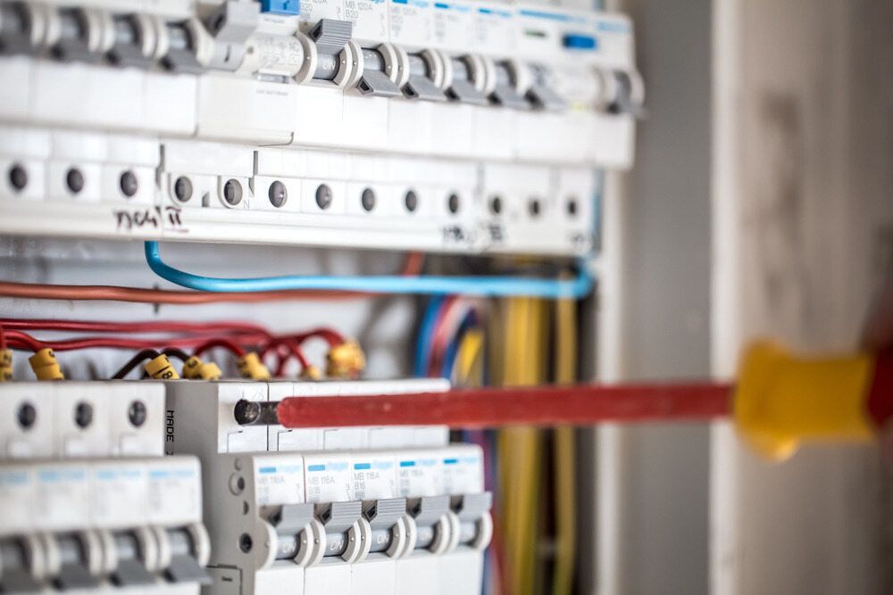 A Close-Up of A Person Using a Red and Yellow Screwdriver on A Residential Electrical Circuit Breaker Panel — AC/DC Electrical, Air Conditioning & Refrigeration In Plainlands, QLD