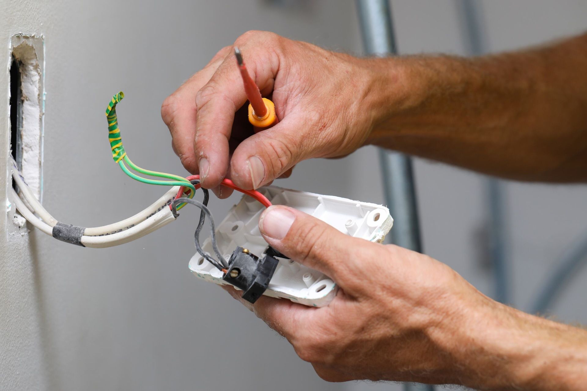 Hands Holding an Electrical Socket and Wires, with A Screwdriver Nearby, While Working on A Wall Outlet — AC/DC Electrical, Air Conditioning & Refrigeration In Highfields, QLD