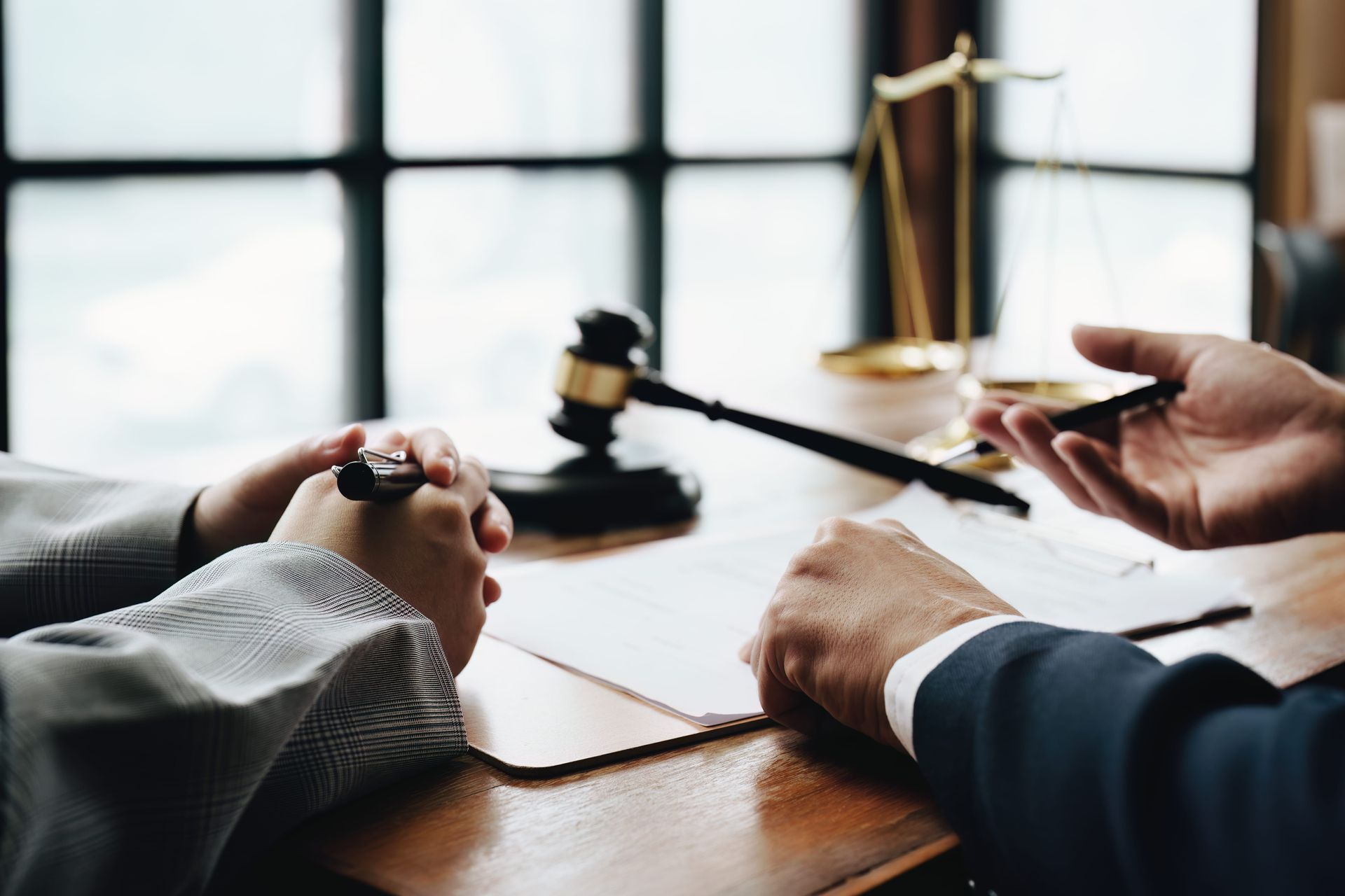 Lawyers reviewing documents at a desk with a gavel and scales of justice in the background