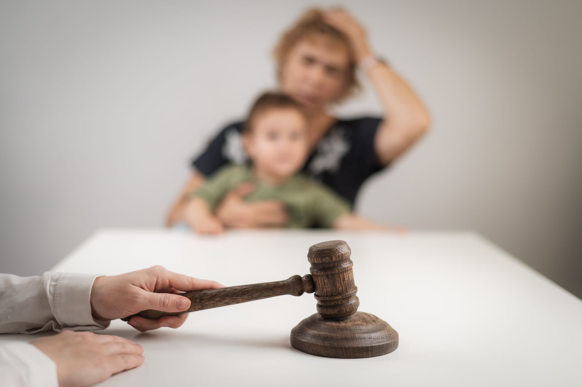 Judge holding gavel, woman comforting child at table.