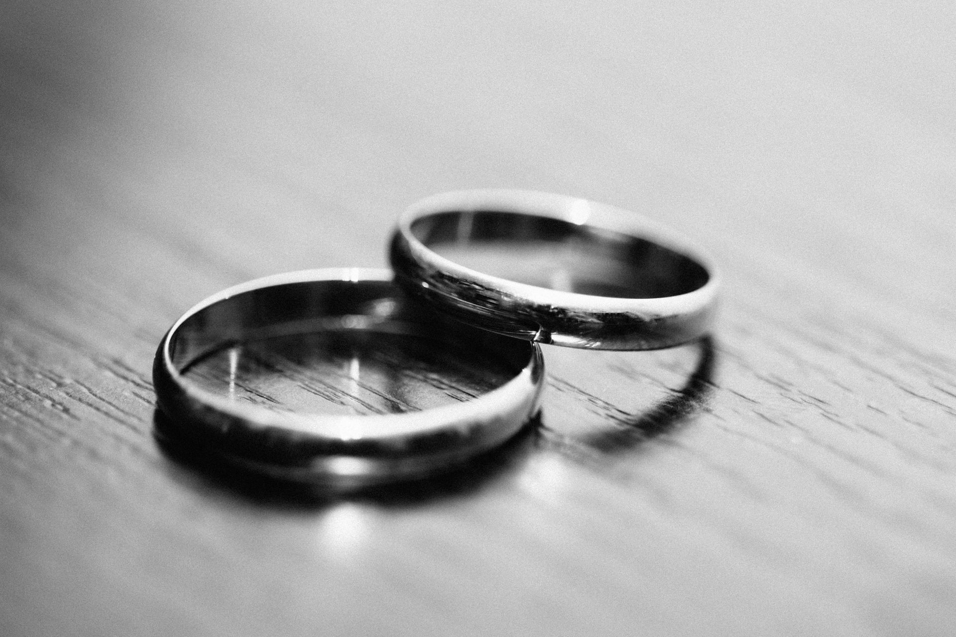 Two wedding rings are sitting on a wooden table.