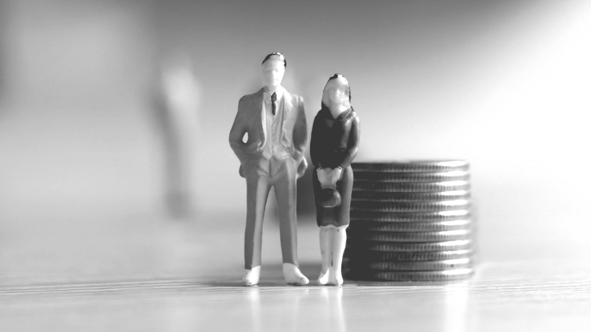 A man and a woman are standing next to a pile of coins.