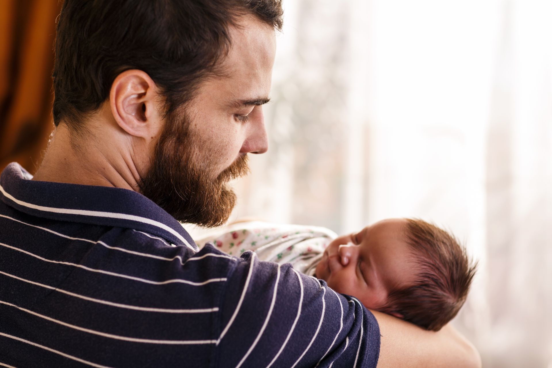 A man is holding a newborn baby in his arms.