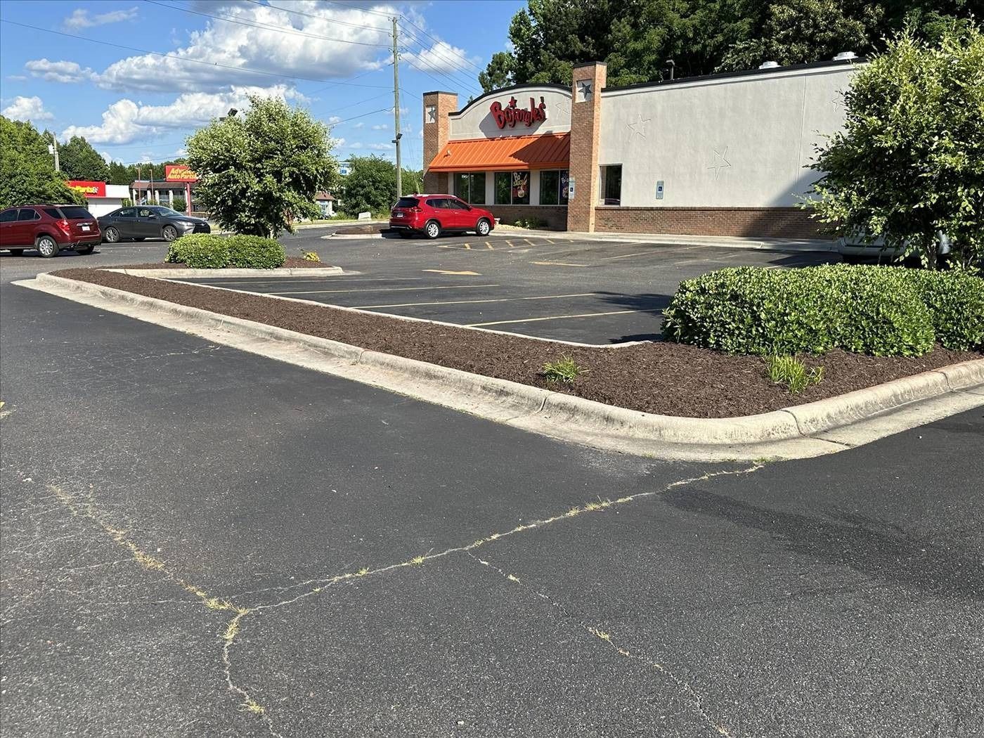 A red car is parked in a parking lot in front of a restaurant.