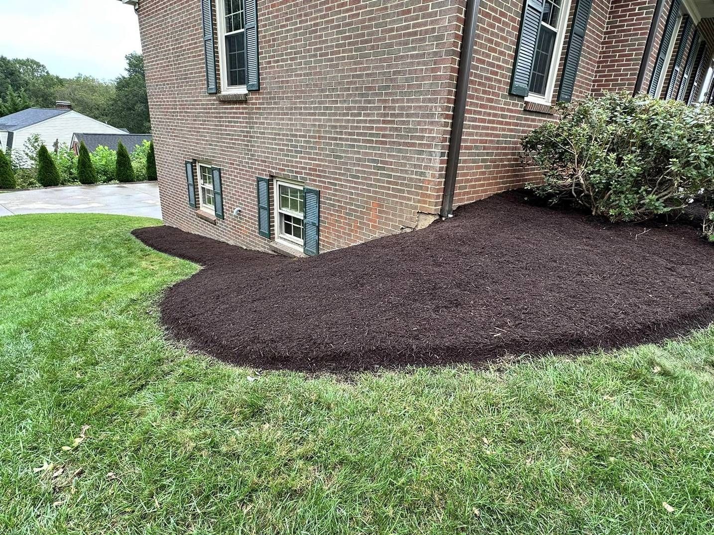 A brick house with a lot of mulch in front of it.