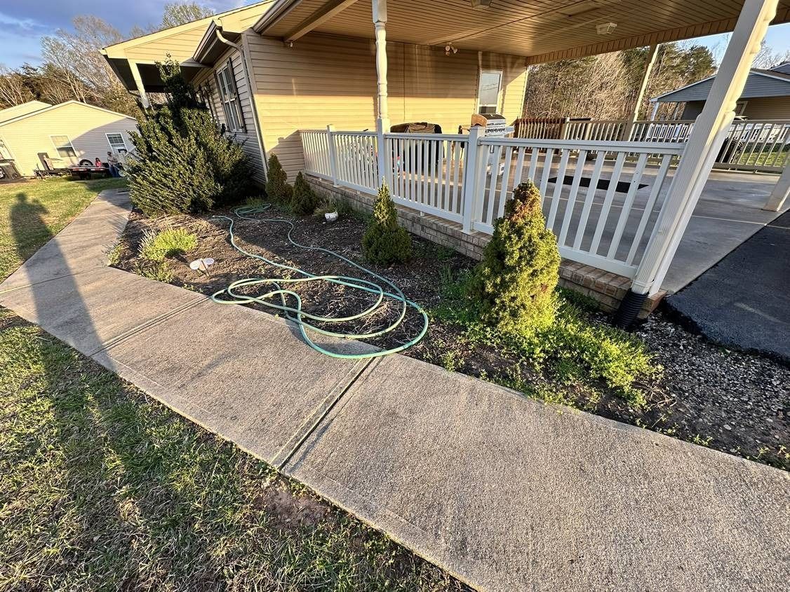 A hose is laying on the sidewalk in front of a house.
