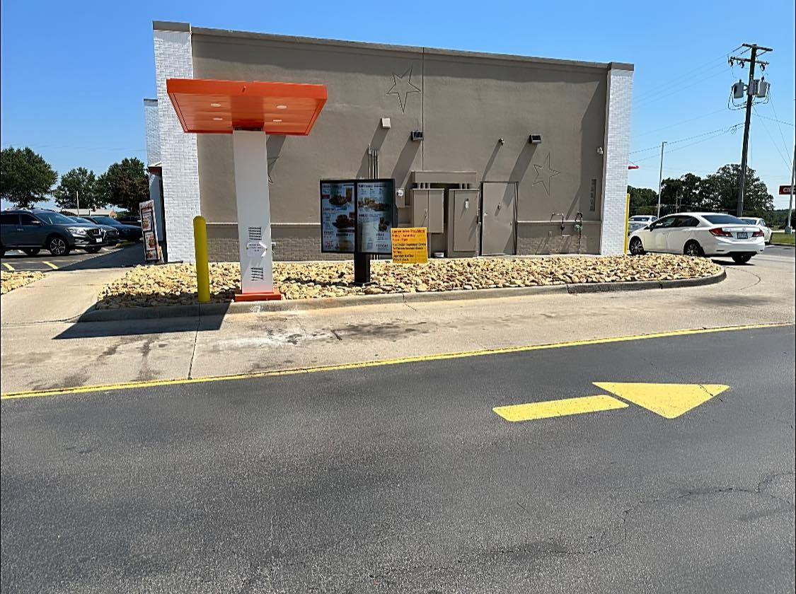 A drive thru at a fast food restaurant with cars parked in front of it.