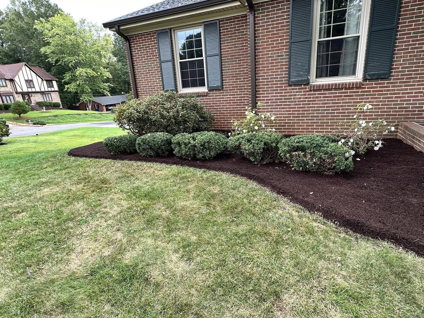 A brick house with a lush green lawn in front of it.