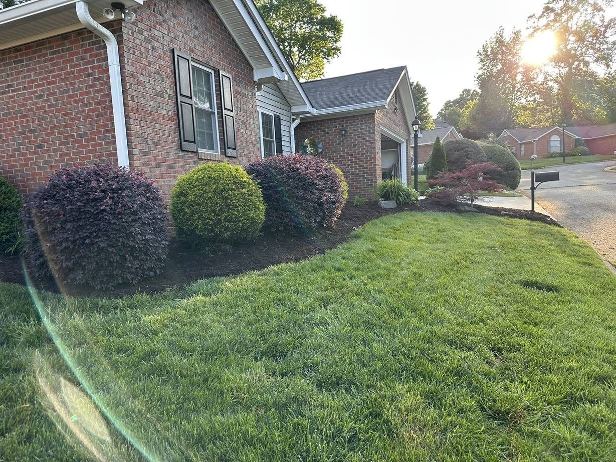 A brick house with a lush green lawn in front of it.
