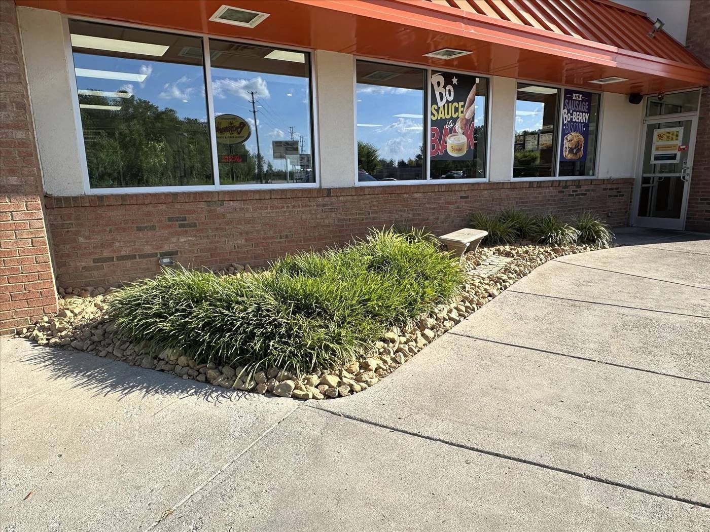 A brick building with a lot of windows and bushes in front of it.