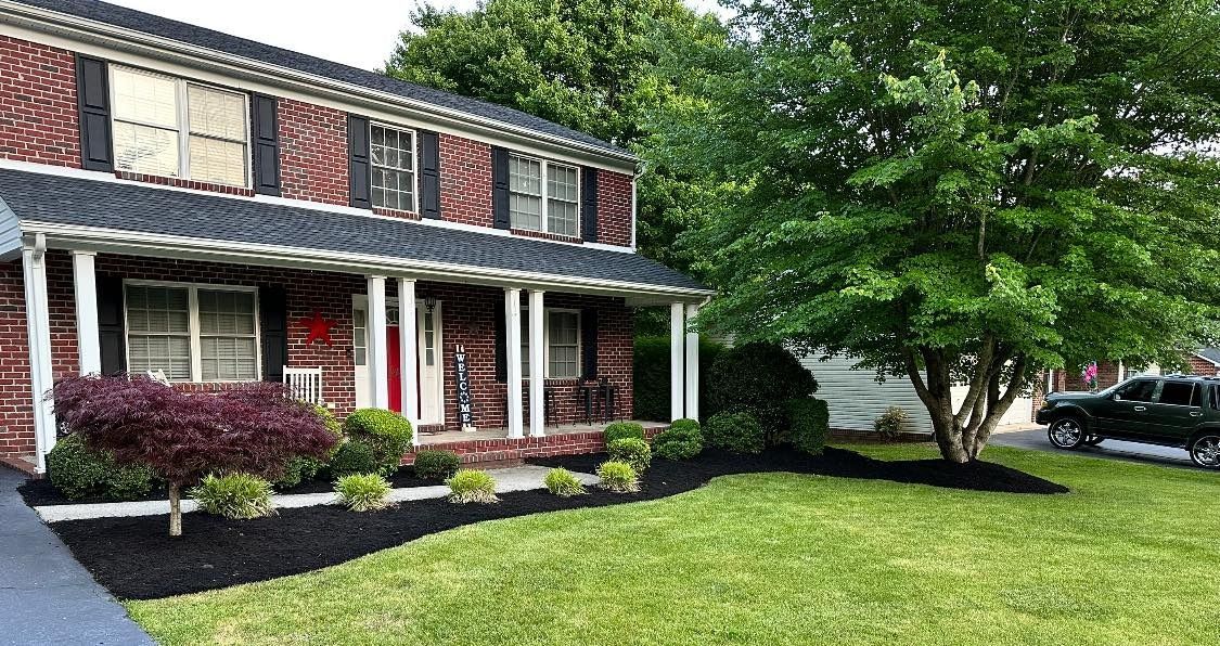 A brick house with a large lawn and a black truck parked in front of it.