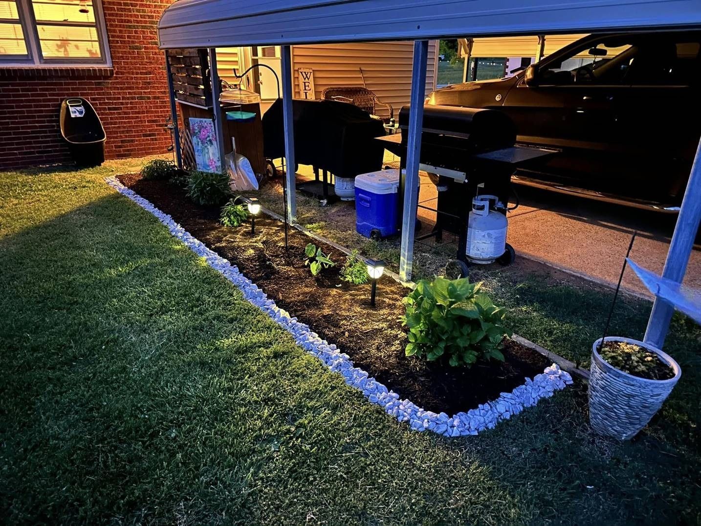 A car is parked under a covered patio in a backyard.