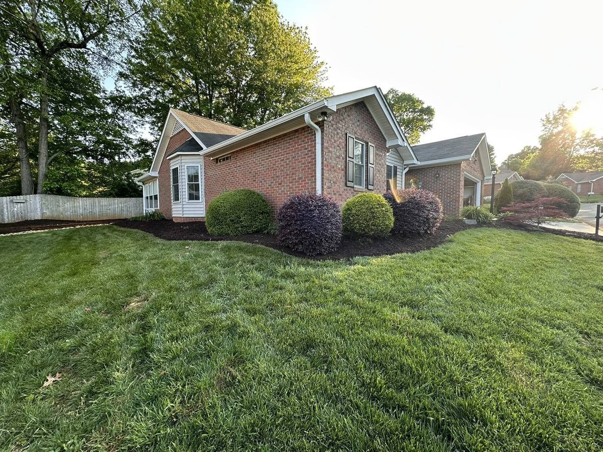 A brick house with a large lush green lawn in front of it.