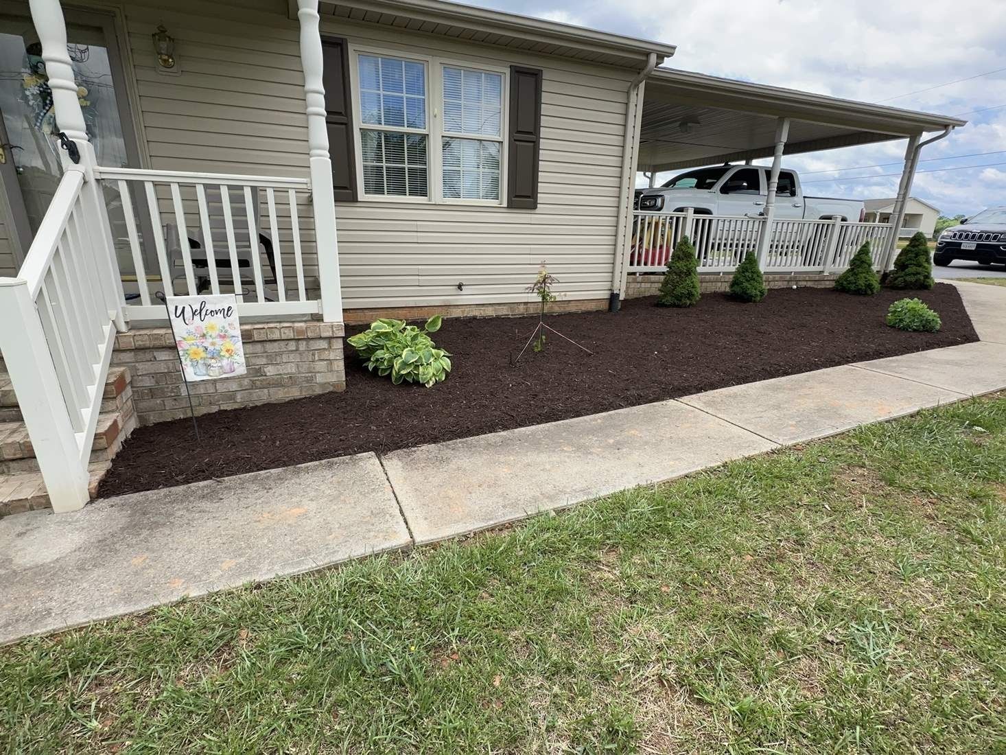 A mobile home with a porch and a sidewalk in front of it.