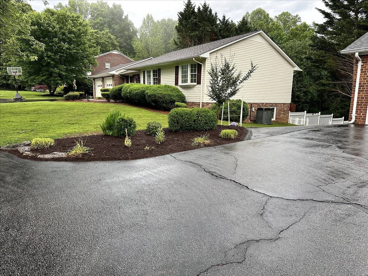 A house with a lush green lawn and a driveway in front of it.