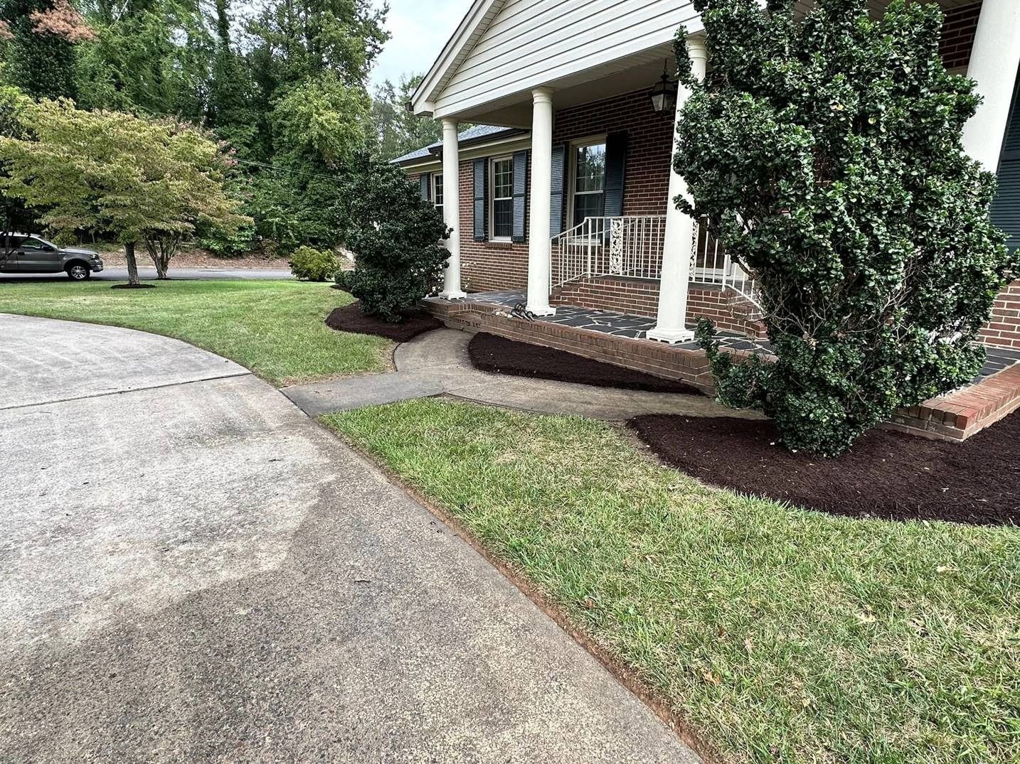 A house with a lush green lawn and a car parked in front of it.