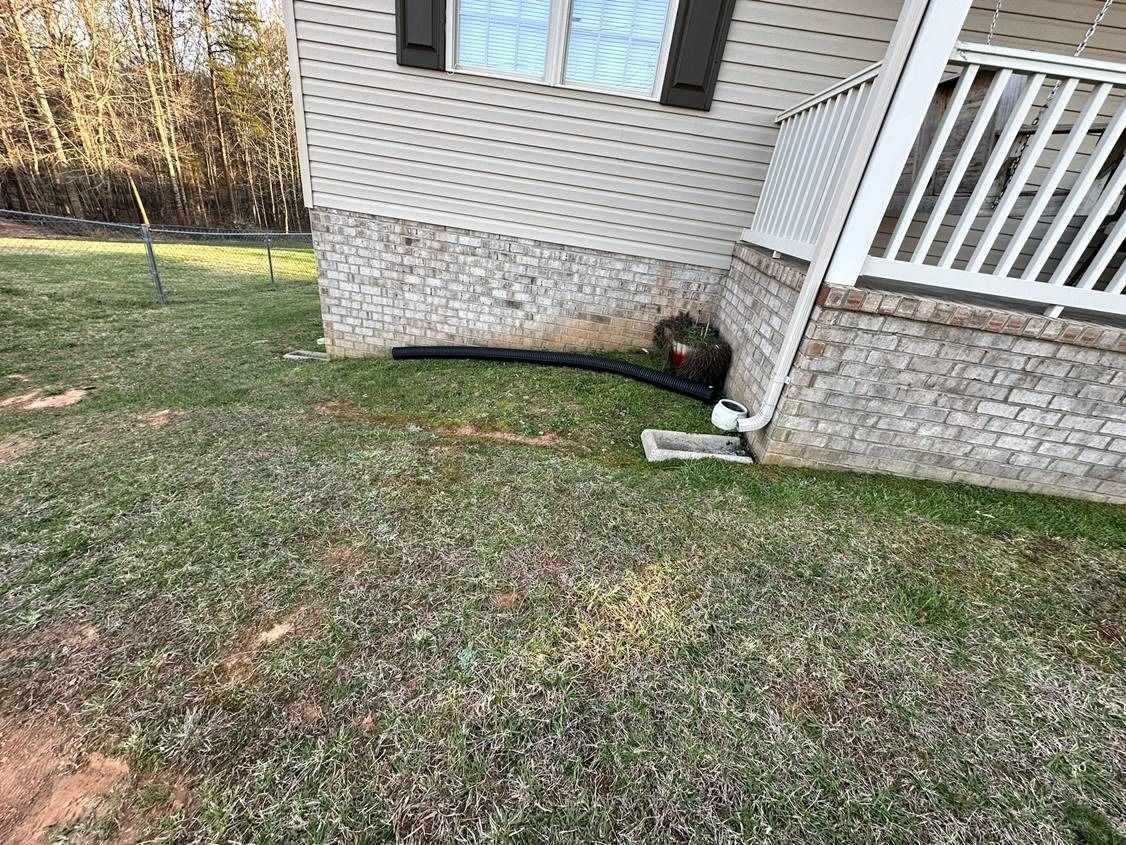 A house with a porch and a drain pipe in front of it.