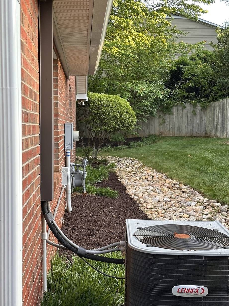 An air conditioner is connected to the side of a brick house.