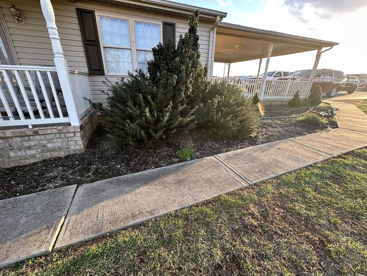 A house with a porch and a sidewalk in front of it.