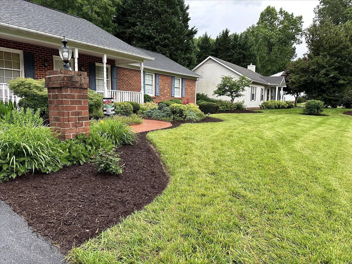 A house with a lush green lawn and a driveway in front of it.