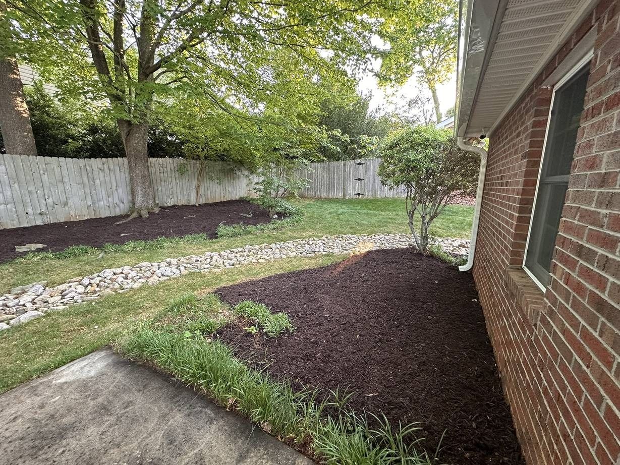 A brick house with a lush green yard and a fence.