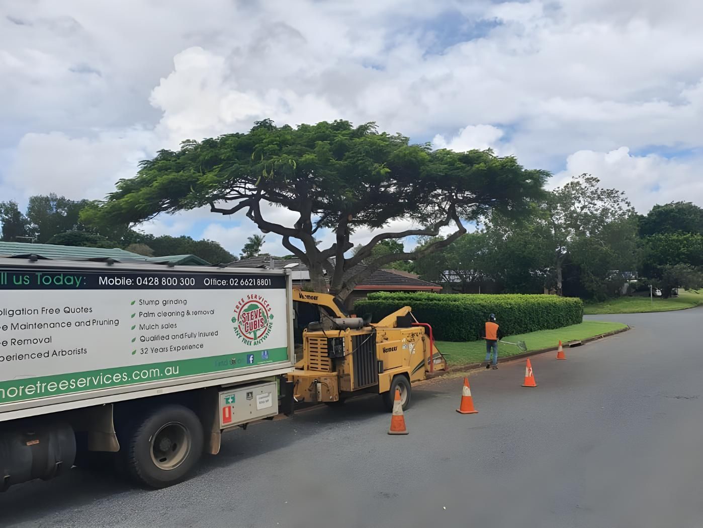 A Truck With a Tree Chipper Attached to It is Parked on the Side of the Road — Steve Cubis Tree Services In Bangalow, NSW