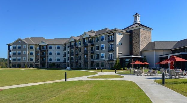 A large building with umbrellas and chairs in front of it