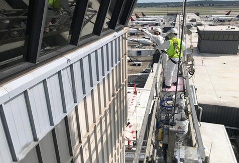 A group of construction workers are working on the side of a building.