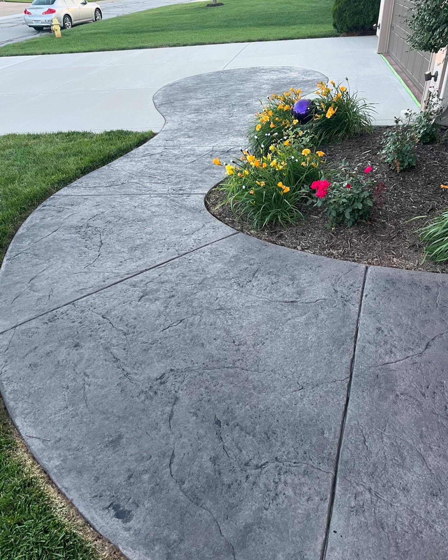 A concrete walkway with flowers in the middle of it.