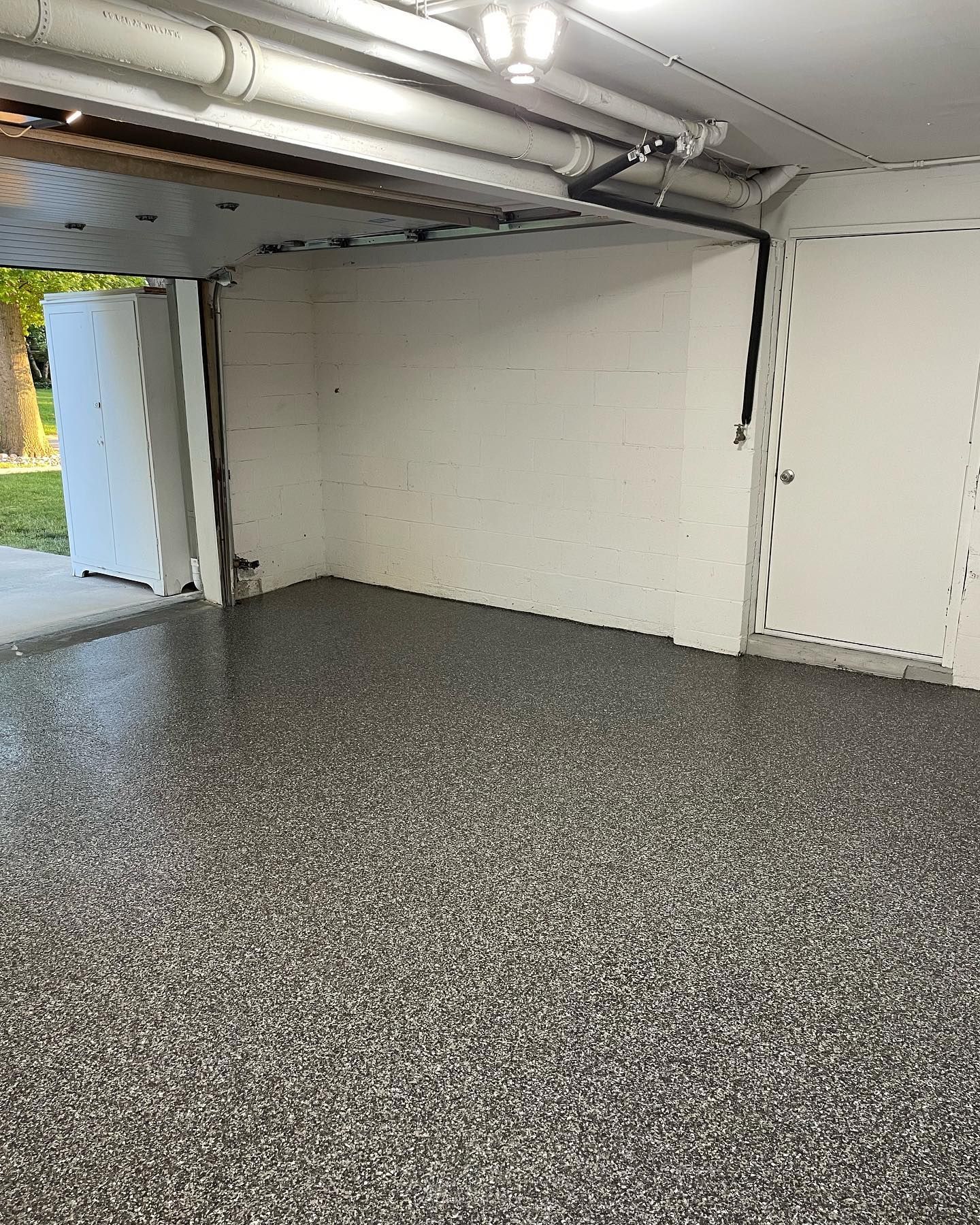 A garage with a gray floor and a white wall.