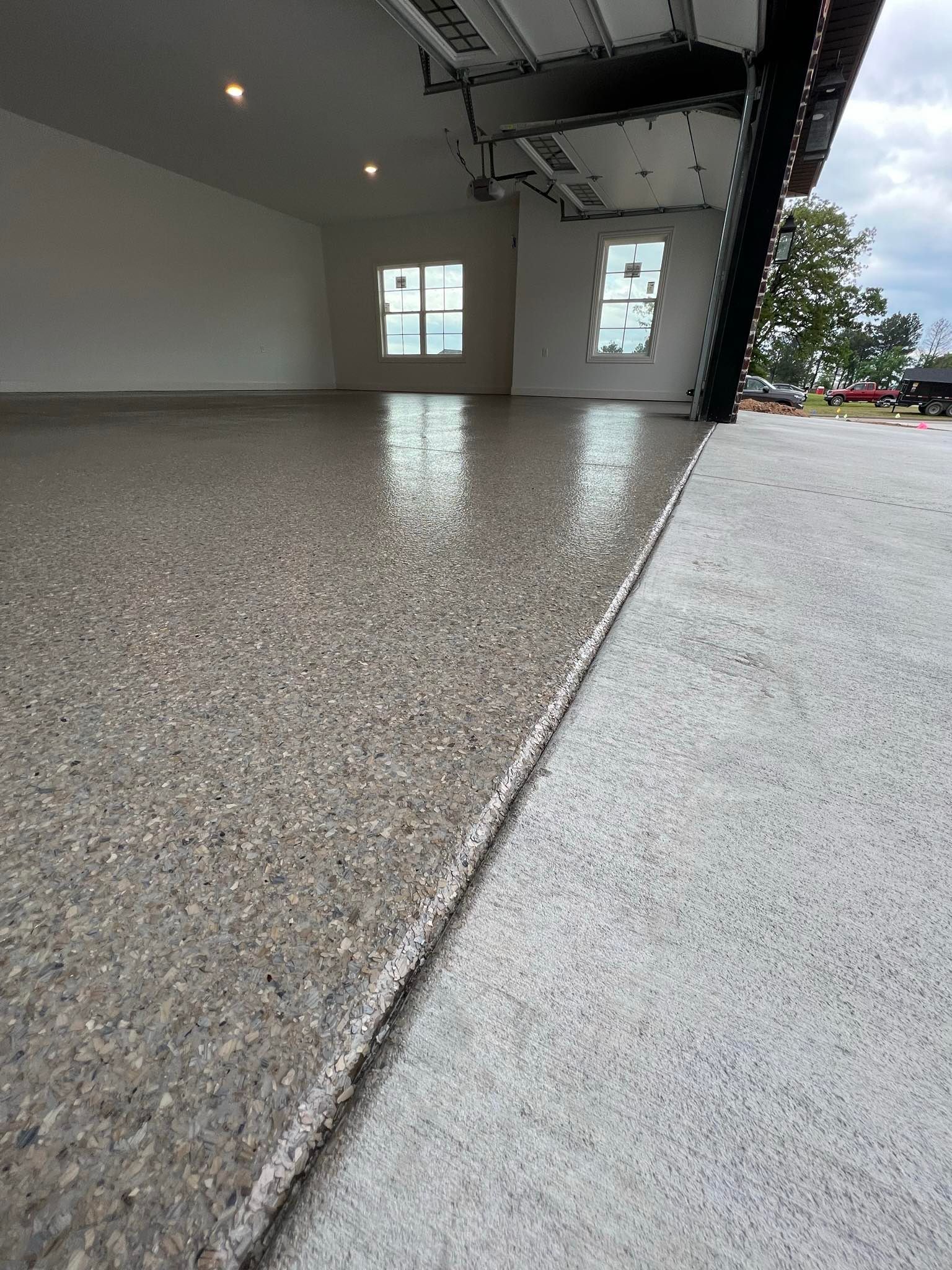 A garage with a concrete floor and a garage door open.