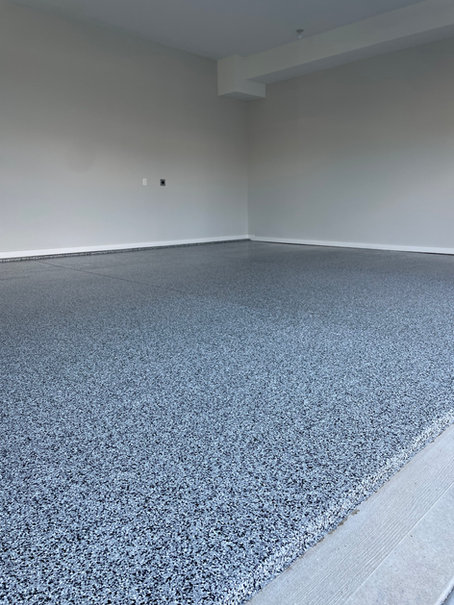 A garage with a gray carpeted floor and white walls.