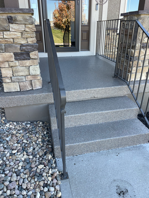 A set of stairs leading up to a house with a metal railing.