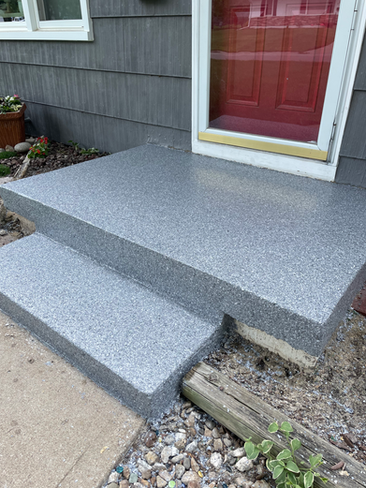 A concrete porch with steps leading up to a red door.