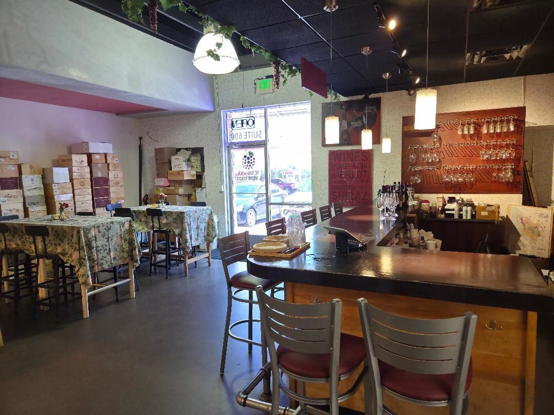 Interior of a cafe with a bar, tables, and chairs. Sunlight streams in through the door.