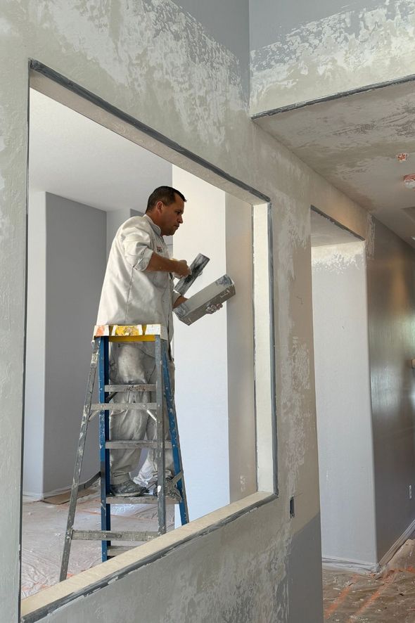 A man is standing on a ladder painting a wall.