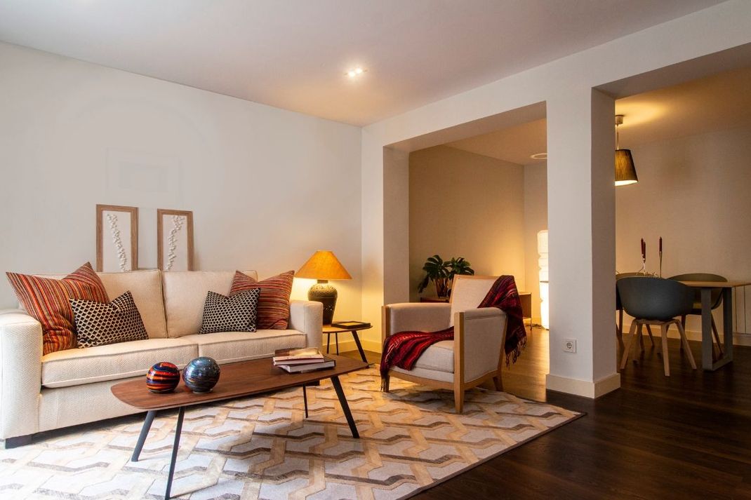 A living room with a couch , chairs , coffee table and rug.
