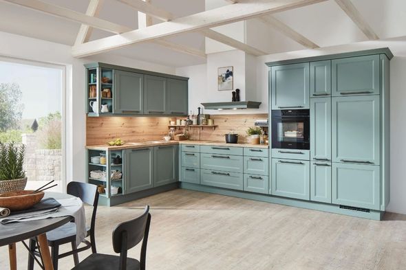 A kitchen with blue cabinets , a table and chairs.