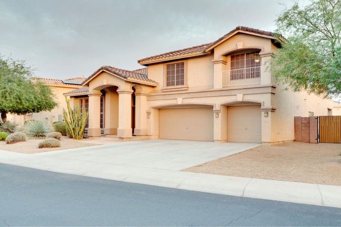 A large house with two garages and a fence in front of it