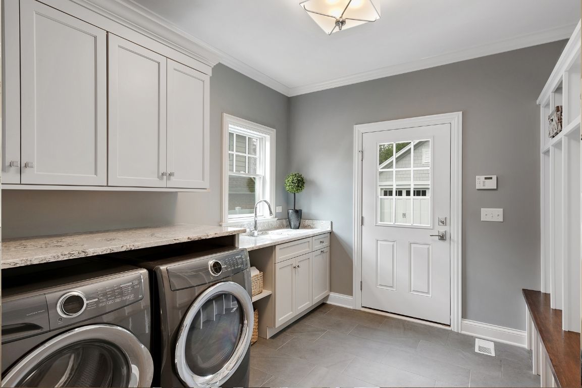A laundry room with a washer and dryer and white cabinets.