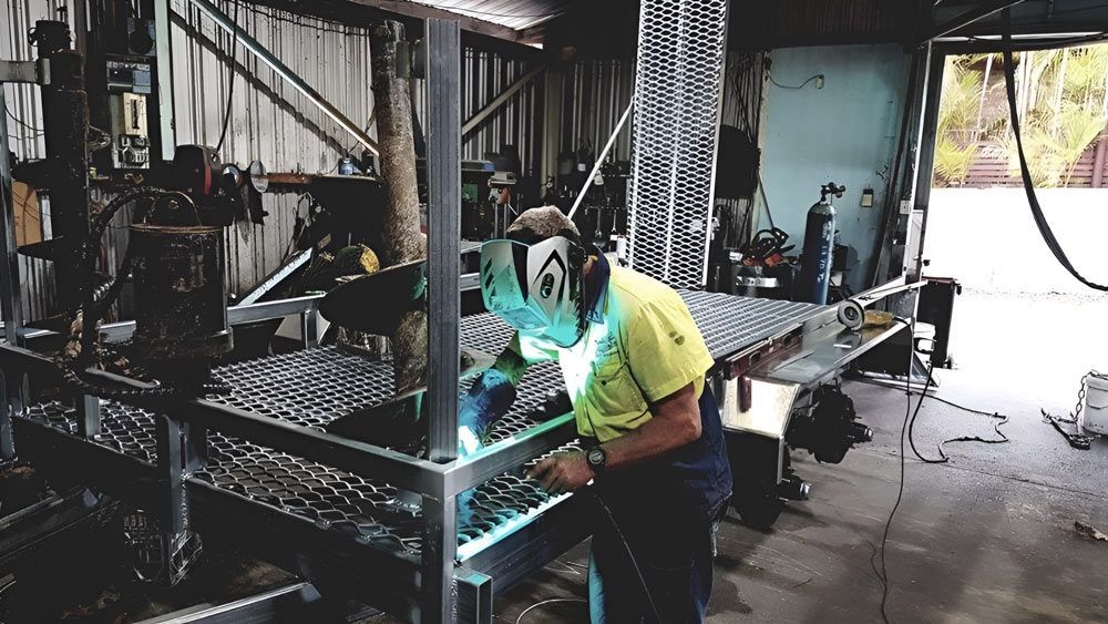 A Man Is Welding A Metal Trailer Structure In A Garage — Hastings Trailer Centre in Port Macquarie, NSW