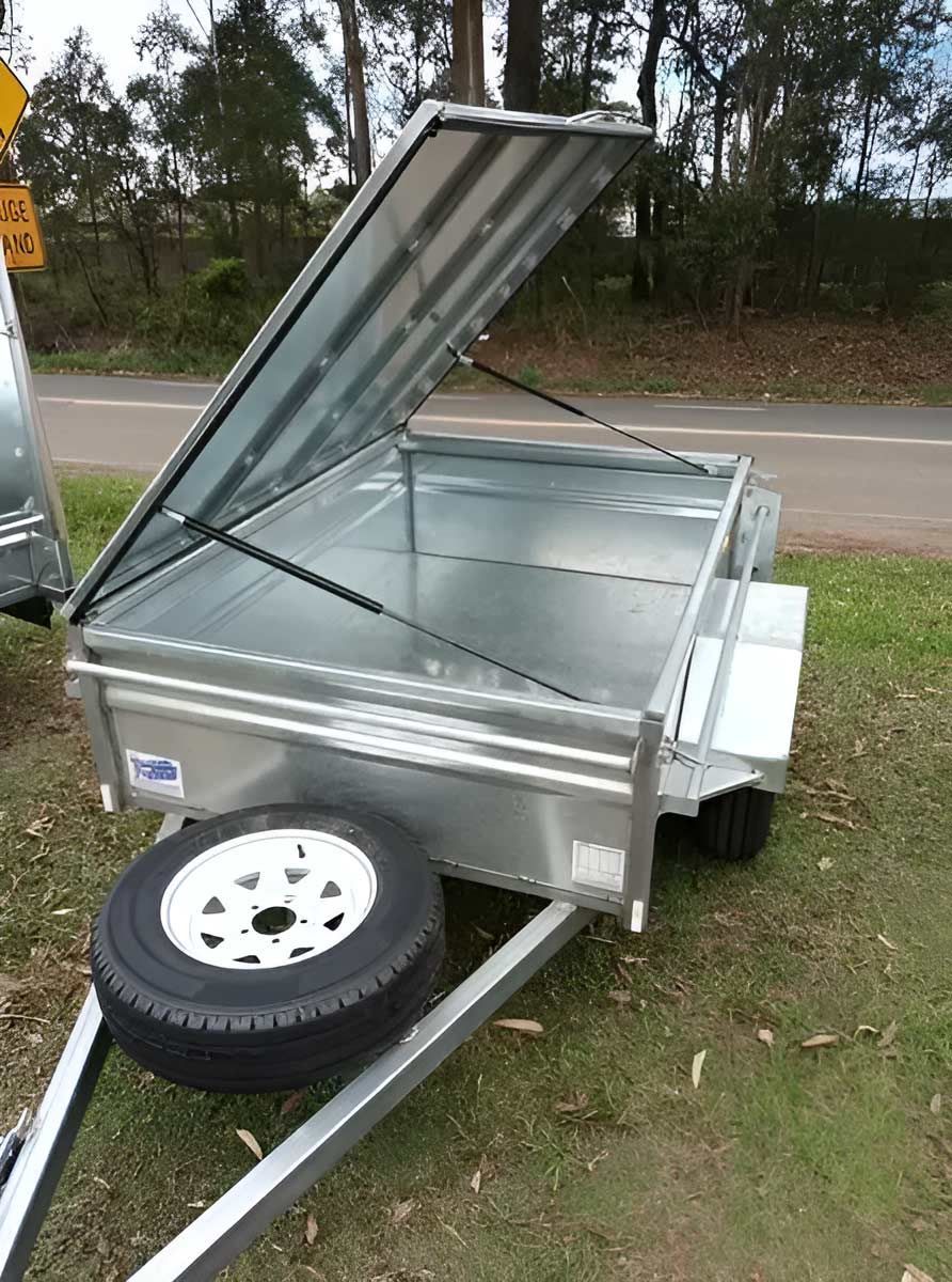 A Newly Trailer With The Lid Open Is Parked On The Grass Next To A Road  — Hastings Trailer Centre in Port Kempsey, NSW