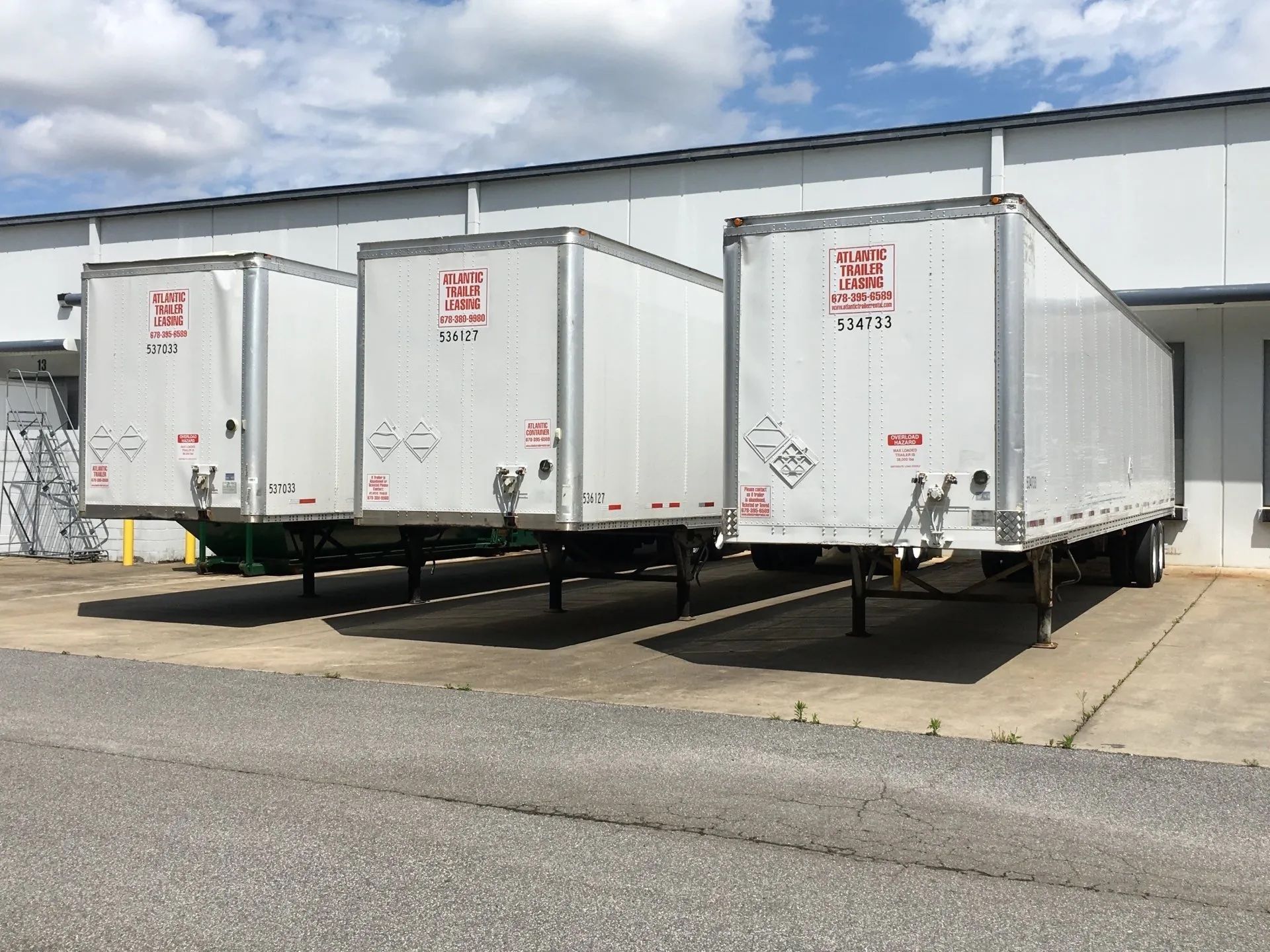 Three semi trailers are parked in front of a building.