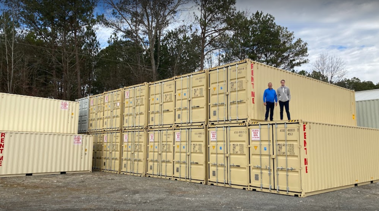 2 people standing on top of a beige shipping container