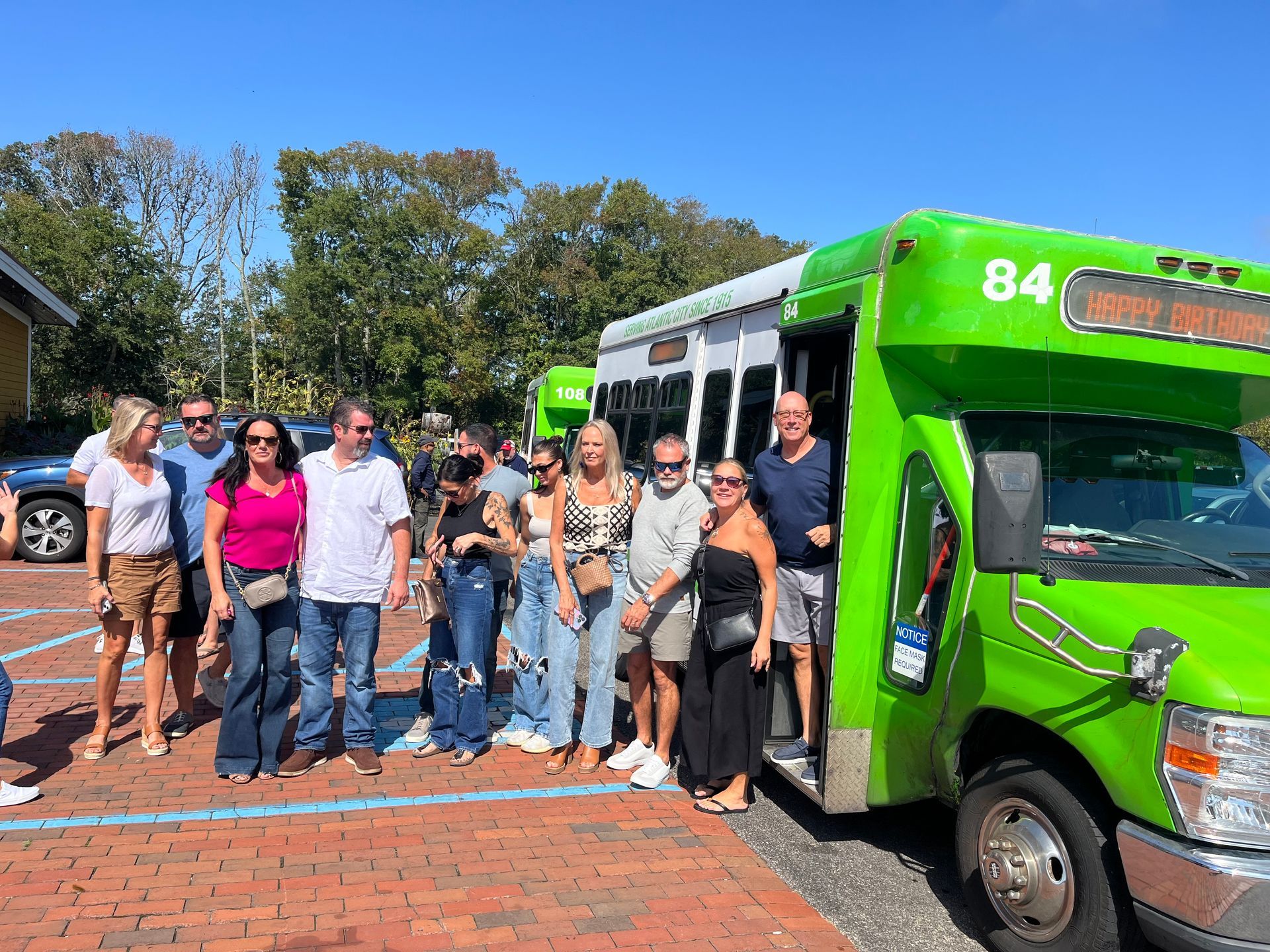 A group of people are standing in front of a green bus.