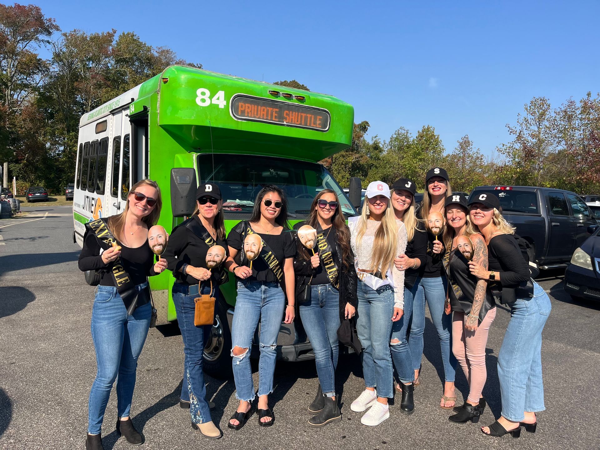 A group of women are standing in front of a green bus.