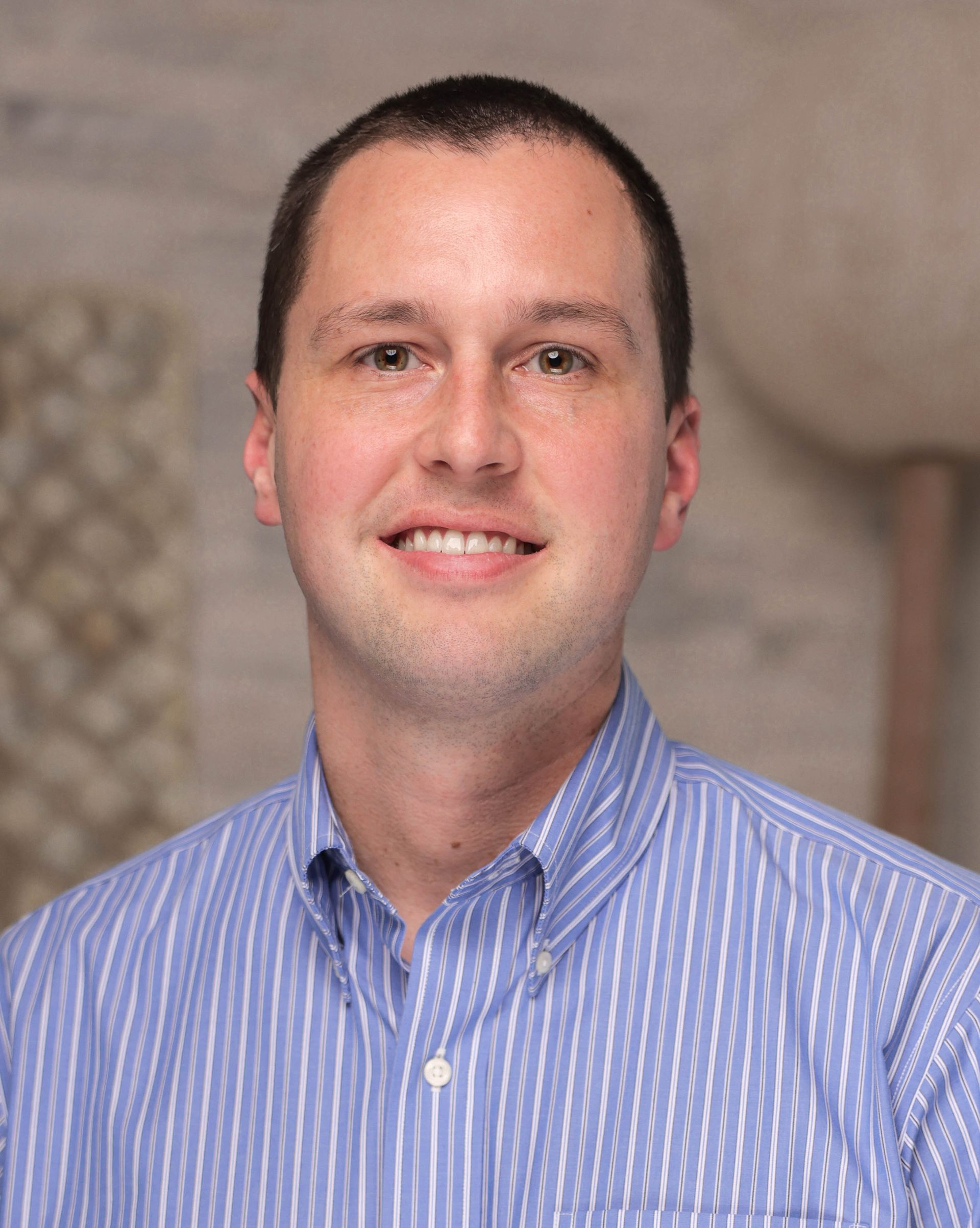 A man in a blue striped shirt is smiling for the camera.